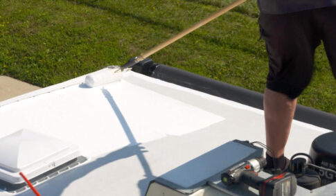 Person using a roller to apply RV Roof Magic